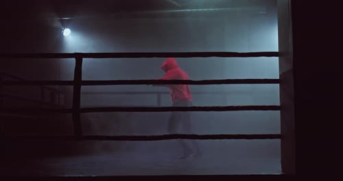Man Training in Boxing Ring at Night