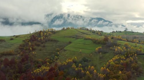 Fly Over Landscapes of Green Hills Under a Layer of White and Fluffy Clouds