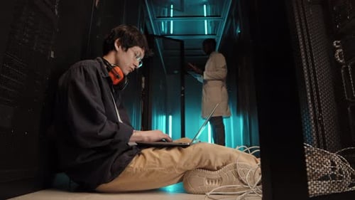 Employee Working with Laptop in Server Room