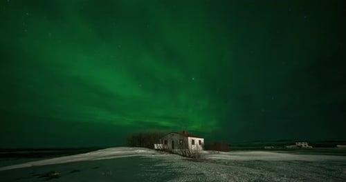 Timelapse of Aurora Borealis Northern Lights Over Small Building in the Show Field. Iceland in the