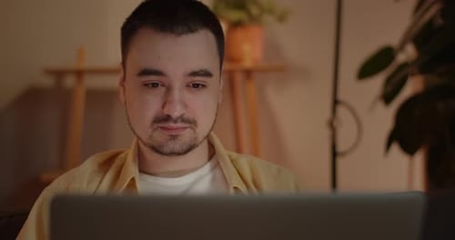 Ausgeschnittene Ansicht eines Mannes, der seinen Laptop benutzt, während er zu Hause sitzt