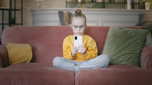 Child Concentrating on Smartphone While Sitting on Couch
