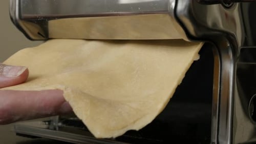 Dough Being Rolled Through a Pasta Machine