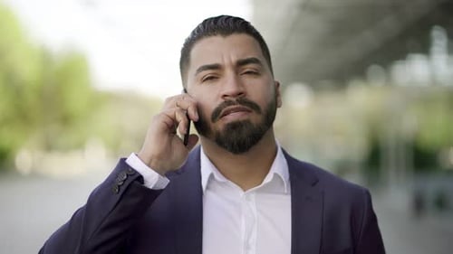 Serious Man Talking on Phone Outside