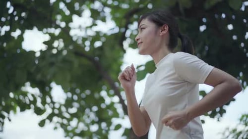 slow-motion of young woman running in park