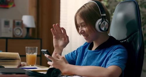 Un adolescente escucha música con auriculares inalámbricos mientras hace la tarea