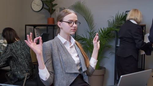 Young Businesswoman Meditates Holds Mind Under Control Practices Yoga Makes Zen Gesture in Office