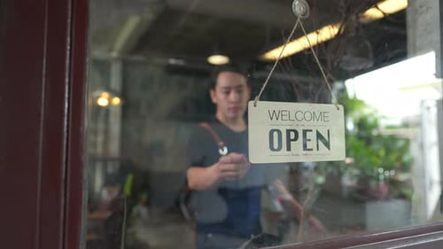 4K Asian man coffee shop owner turning hanging open sign to closed on the door