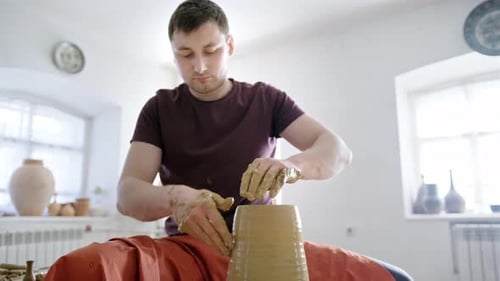 Man Shaping Clay on Pottery Wheel in Studio