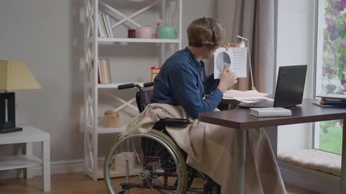 Un homme caucasien expert en conférence en fauteuil roulant en ligne pointant du doigt un graphe parlant au Ralenti