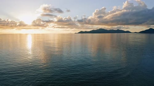 Aerial Footage of Sunset and Open Calm Ocean with Tropical Island Silhouette on Horizon