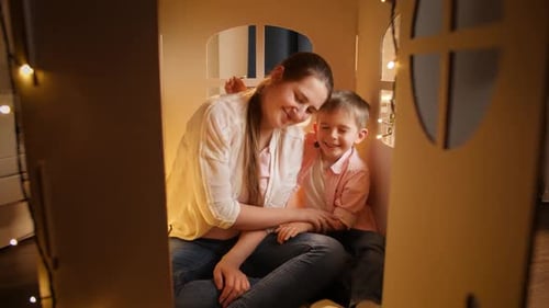 Happy Mother and Child Embracing in Cardboard House