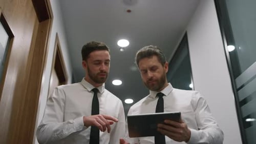 Couple Managers Discussing Business Project Using Tablet Pad in Office Hallway