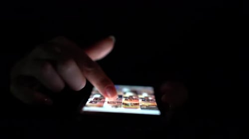 Woman Using Smartphone Evening Time. Close Up. Black Background