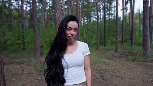 Frau steht neben einem Baum in einem Wald