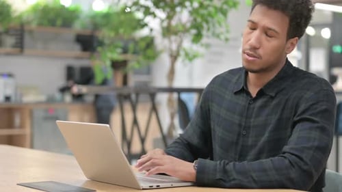 Man Works at Laptop and Stretches Back