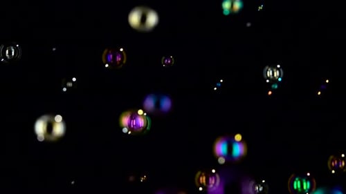 Floating Soap Bubbles in the Air Close Up. Slow Motion. Black Backgroungs