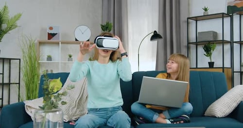 Niña usa auriculares de realidad virtual cerca de su hermana menor que aplica la computadora