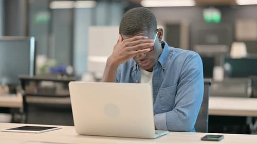 Tired Man Working on Laptop in Modern Office