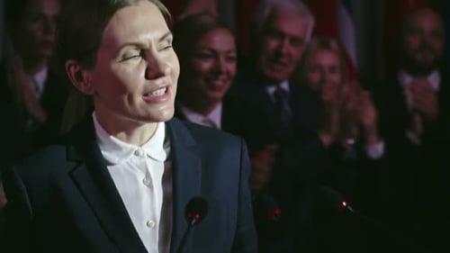 Woman Speaks at Podium to Applauding Crowd