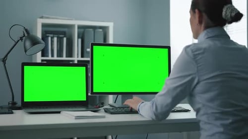 Woman Using Two Green Computers