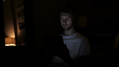 Young Man Using Tablet Device in Dark Room at Night