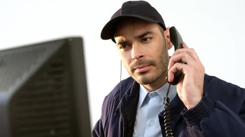 Wachmann telefoniert während der Arbeit am Computer