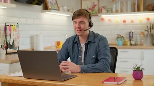 Man with Headset Using Laptop for Online Meeting