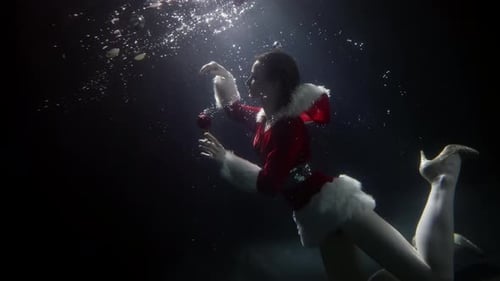 Slim Woman Dressed Santa Suit Is Floating Underwater Mascarade and Costume Party in Pool