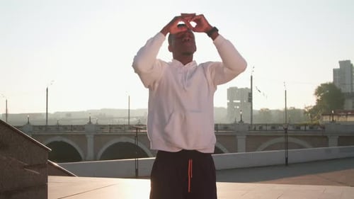 Man Stretching in Sunrise on Urban Promenade