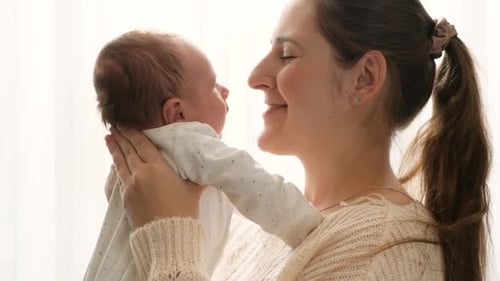 Loving Mother Cradling Newborn Baby at Home
