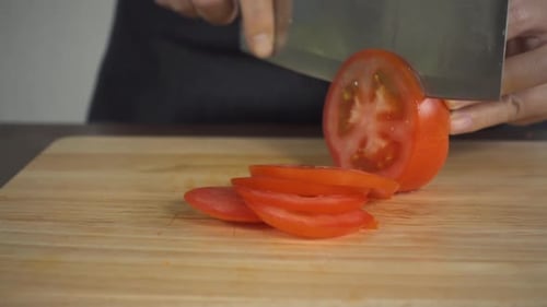 Hands Slicing Tomato With Knife on Cutting Board