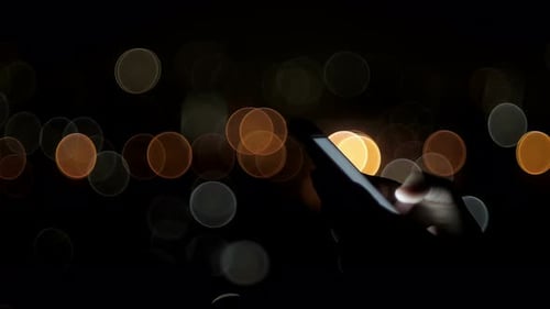 Hand Uses Smartphone in Nighttime Bokeh