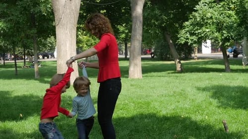Joyeuse mère tournante faisant un cercle torsadé avec ses petites filles. Ralenti