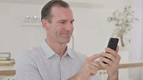 Man Scrolling on Phone Indoors During the Day