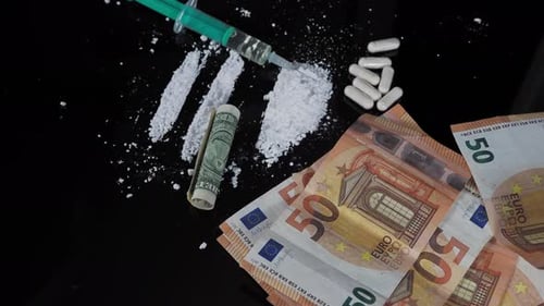 Money, Drugs, and Syringe on a Shiny Surface