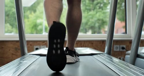 Closeup Athletic Feet Running on Treadmill in Fitness Gym