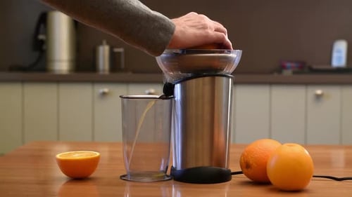 Man Juicing Fresh Oranges with an Electric Juicer