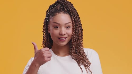 Woman Gives Thumbs Up on Orange Background