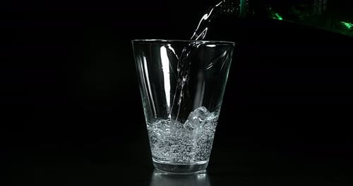 Wasser wird vor schwarzem Hintergrund in Glas gegossen, Zeitlupe 4K