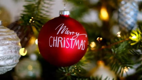Merry Christmas.Red christmas ball close-up on christmas tree with shining garland