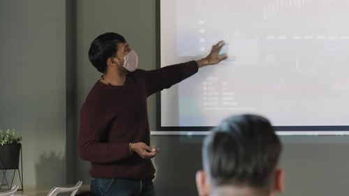 Masked Presenter Explains Data in Modern Office