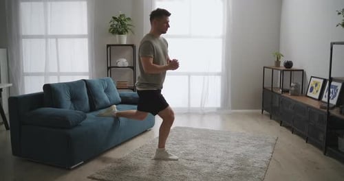 Adult Athletic Man Is Squatting in Room During Daily Workout Training Alone at Home During