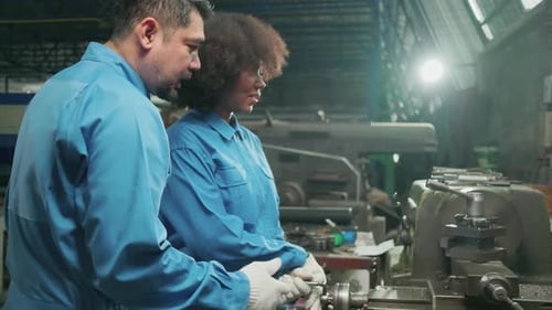 Two professional industry workers work in metalwork manufacturing factory.