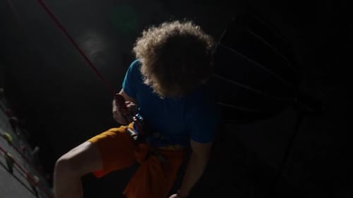 Adult Climbing Indoor Rock Wall with Rope at Night