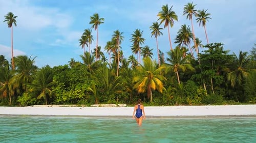 Slow motion: woman walking on white sand beach turquoise water tropical coastlin