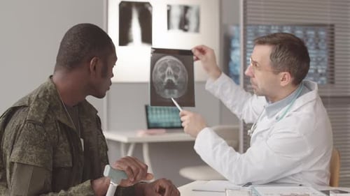 Doctor que muestra al soldado su radiografía orbital