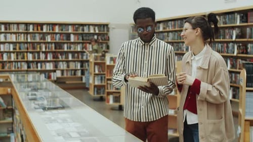 Multiethnic Man and Woman Discussing Book in Library