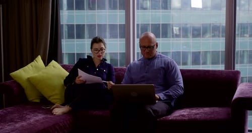 Geschäftspartner diskutieren Probleme beim Sitzen auf lila Sofa