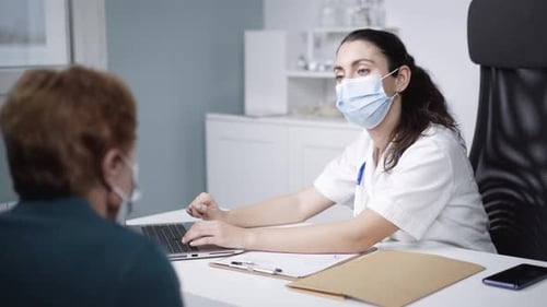 Physician talking to unrecognizable patient during checkup in clinic